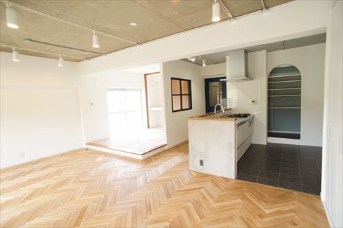 ヘリンボーンの無垢の床材と小上がりの和室が繋がるモダンLDK